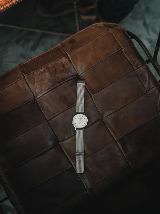 Elegant silver wristwatch resting on a brown leather seat, showcasing elegance and style.