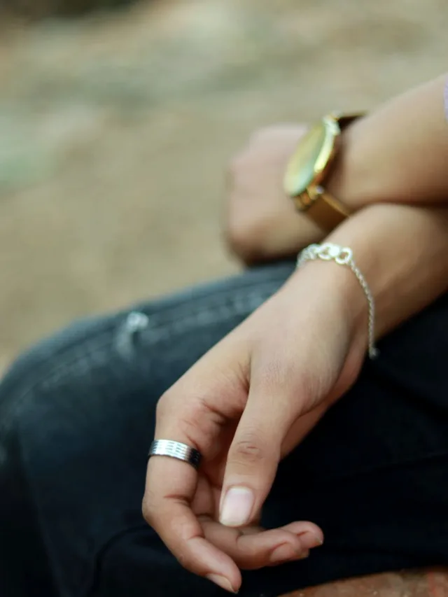 A close-up view of hands resting, showcasing a watch and rings.