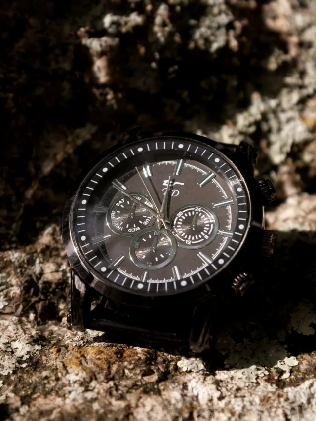 Close-up of a stylish wristwatch displayed on a textured rock, showcasing time precision.